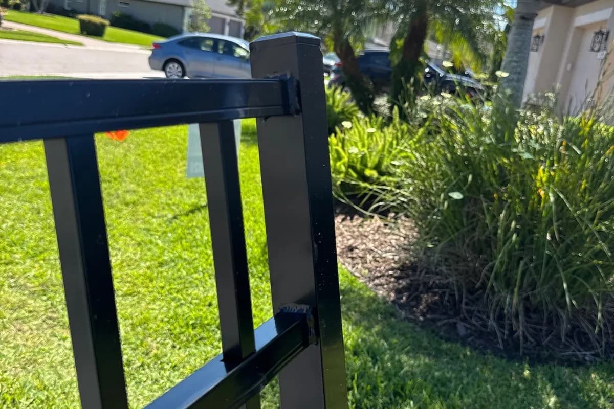 Black aluminum fence and pedestrian gate beside a home