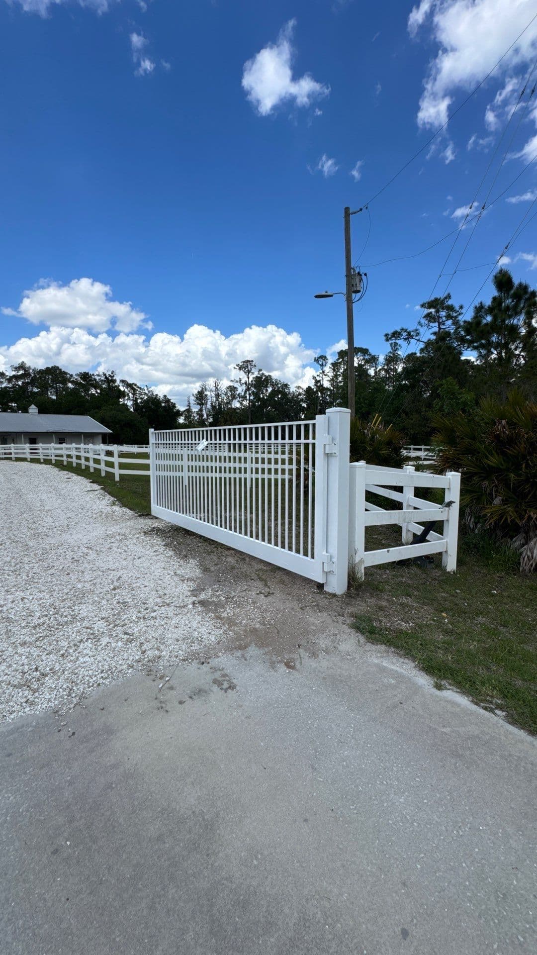 White driveway swing gate with its full frame, hinge post and operator visible