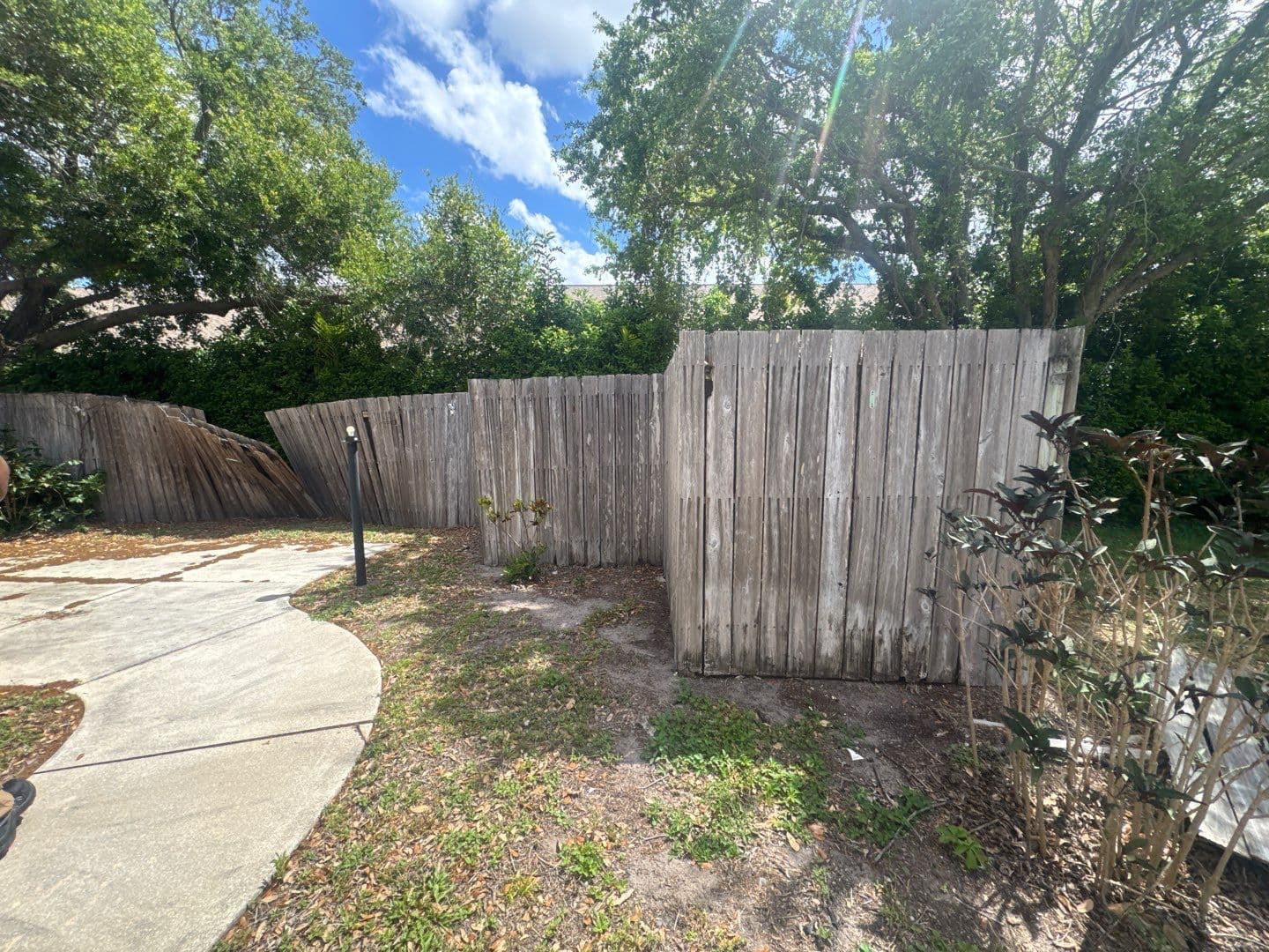 Leaning and damaged wood fence sections before repair